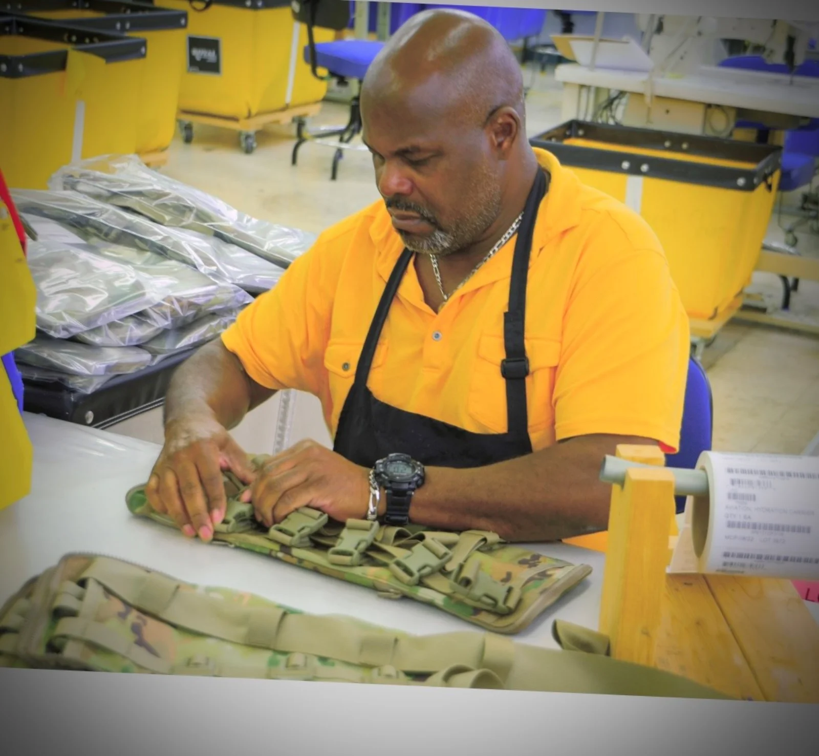 A Lions Services production team member assembling tactical gear at a workstation in the Charlotte manufacturing facility