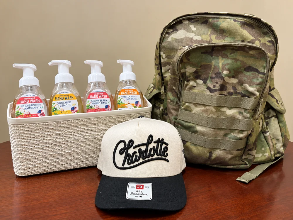 Camouflage backpack, a Charlotte trucker hat and a basket of four foaming hand soaps.